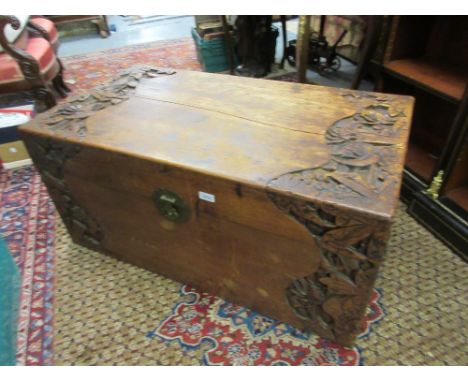 Oriental carved camphor wood trunk decorated in deep relief with stylised flowers, the hinged lid above a brass hasp and stap