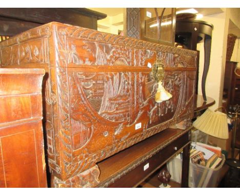 Antique Chinese camphor wood trunk carved in high relief with figures, buildings and buffalo, having character mark to front 