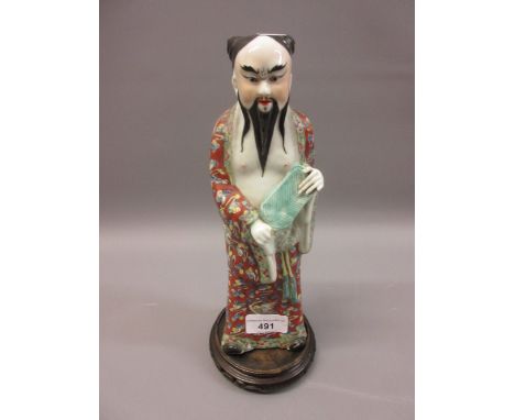 Chinese porcelain enamel decorated figure of a standing sage on hardwood stand, 10.5ins high 