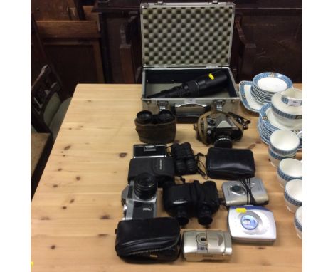 A case containing camera lens and a collection of various cameras, binoculars, Walkmans etc.