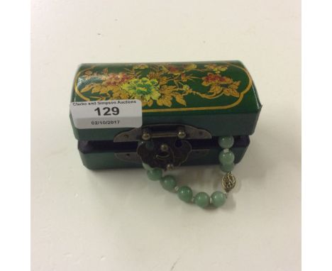 A jade coloured bead necklace with white metal clasp contained in dome topped box