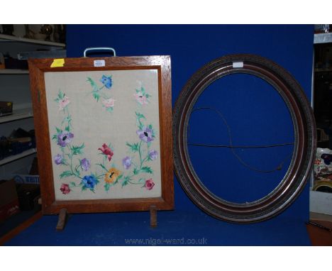 An Oak Fire screen with floral embroidery panel and a carved wooden oval picture frame, 21'' x 25''.