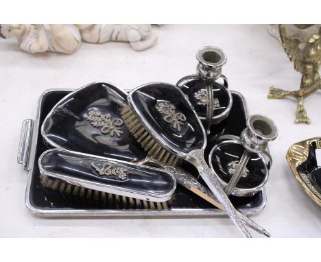 A VINTAGE BLACK DRESSING TABLE VANITY SET TO INCLUDE A HAND MIRROR, TWO BRUSHES AND TRAY - PLUS TWO CANDLE STICKS 