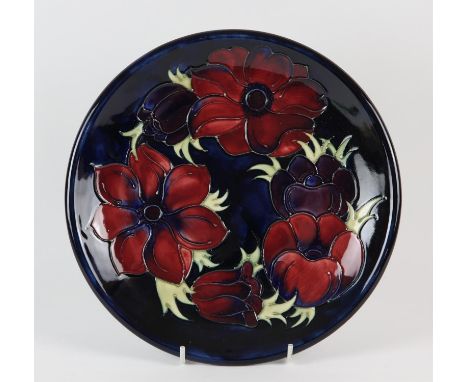 MOORCROFT, an Anemone design plate with pink and mauve coloured flowers on a blue background, 26cm diameter, together with tw