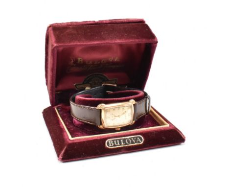 A vintage Bulova rolled gold boxed wristwatch. The watch having a contoured rectangular champagne coloured dial with gold ton