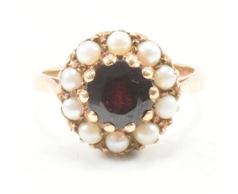 A 9ct gold garnet and pearl cluster ring. The ring set with a central garnet framed by pearls to 9ct gold setting. Marked 9ct
