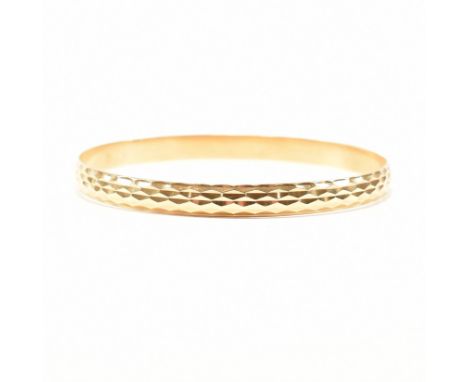 A vintage yellow metal bangle bracelet. The bangle / armlet of circular D form having faceted detailing to the exterior. Cont