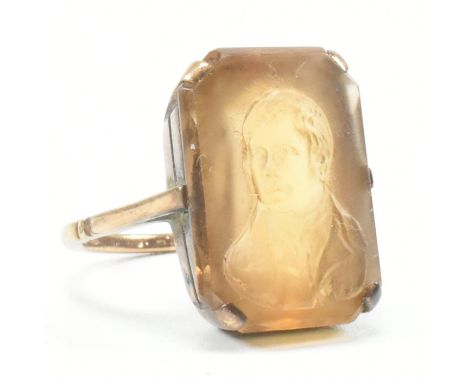 An antique yellow metal and citrine cameo ring. The ring having a rectangular cut yellow stone carved to depict a portrait of