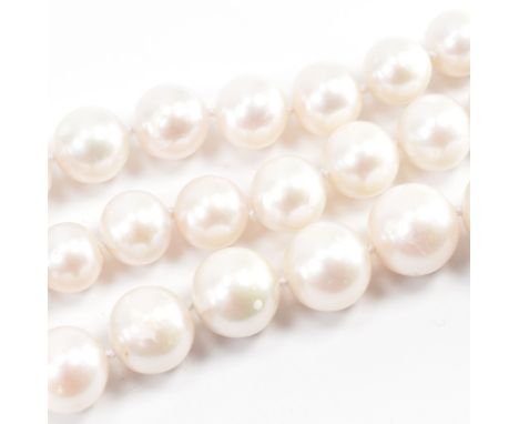 A large cultured pearl necklace. The necklace having round pearls on a knotted thread with a magnetic silver clasp. Measures 