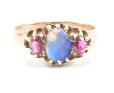 An early 20th century gold opal and ruby ring. The ring set with a central oval opal cabochon flanked by two oval cut rubies.