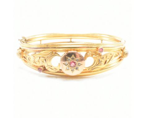A 19th century gold gem and diamond set hinged bangle. The bangle set with a central garnet framed by a halo of rose cut diam