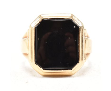 A vintage 14ct yellow gold and onyx signet ring. The ring having a canted rectangular head with stepped bezel set black stone