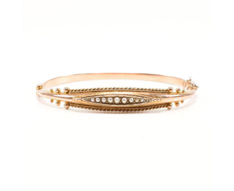 A Victorian hallmarked 9ct rose and yellow gold and pearl bangle bracelet. The hinged bangle having a navette head set with a
