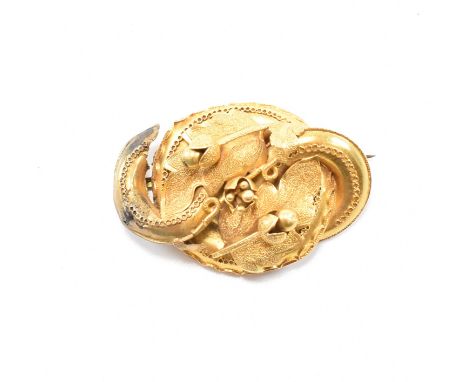 An antique yellow metal brooch pin. The brooch of twisted form having textured and moulded metal to depict foliate oak leaves
