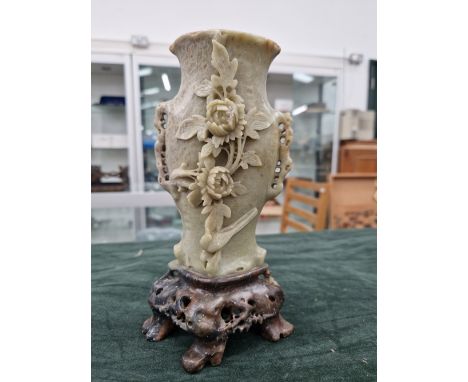 A CHINESE CELADON GREEN CARVED JADE SOAPSTONE VASE ON AN OPENWORK STAND WITH FOLIATE, FLORAL AND BIRD DECORATION.