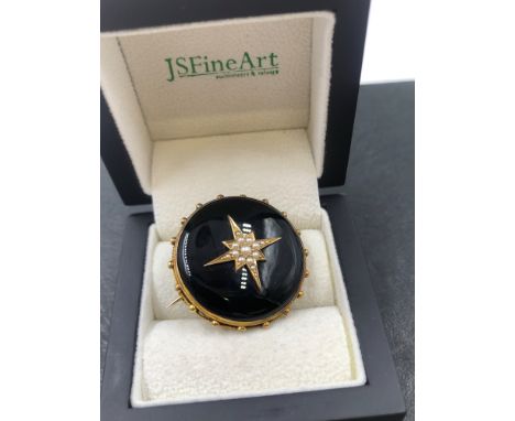 AN ANTIQUE MOURNING BROOCH WITH GLAZED PANEL BACK AND A SEED PEARL STAR CENTRE. DIAMETER 3.2cms. NO ASSAY MARKS, ASSESSED VAR