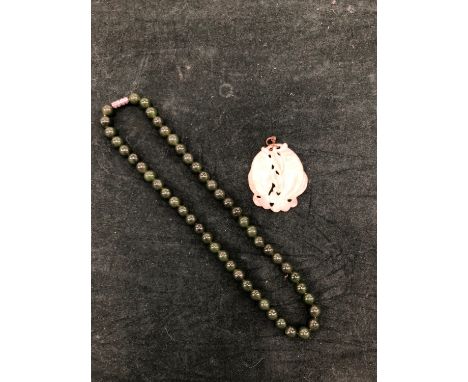A ROW OF SPINACH GREEN JADE BEADS WITH A SCREW BARREL CLASP, LENGTH 42cms, TOGETHER WITH A CARVED PALE JADE TWIN FISH AMULET.