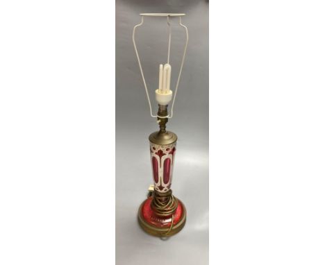 A 19th century Bohemian overlay ruby glass lamp, on engraved brass plinth, 34cm excluding light fittingsCONDITION: Ruby glass