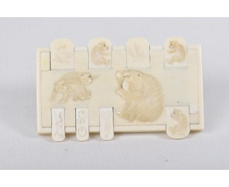 A Japanese carved ivory gaming or Bezique markerThe rectangular panel carved and stained with monkeys, applied with eight tab