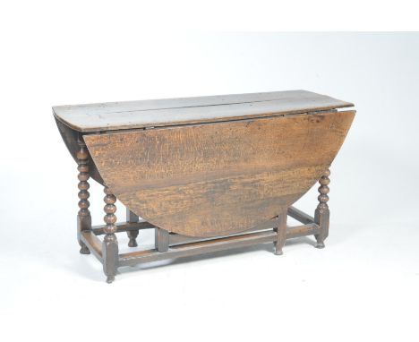 An 18th century oval oak gate leg dining tableThe oval plank top supported on nicely turned bobbin supports with plain cross 