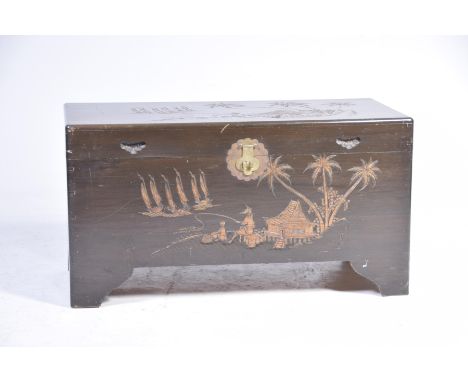 A Chinese camphor wood chestThe rectangular top incised with a landscape scene depicting figures fishing with palm trees and 