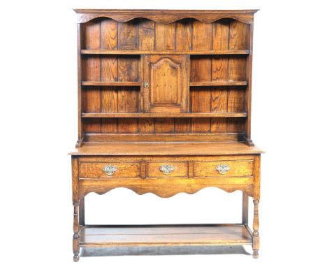A good quality Georgian style oak dresserWith a moulded cornice above a shaped frieze and a central fielded panelled cupboard