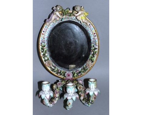 A DRESDEN AUGUSTUS REX OVAL MIRROR surmounted by two cupids and fitted with three scrolling candle branches.Augustus Rex mark