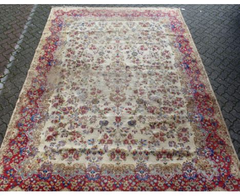 A Kerman carpet, cream ground with floral decoration within red ground borders. 12ft 10ins x 8ft 10ins.