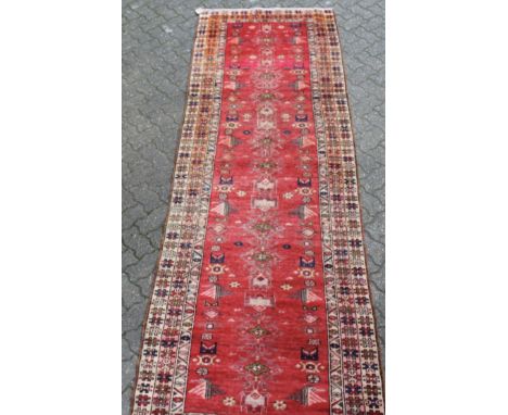 A HAMADAN LONG CARPET, bright red ground within a stylized triple border. 10ft 10ins x 3ft 7ins.