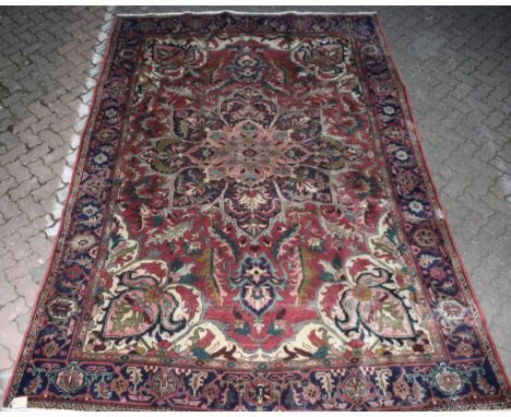 A Heriz design claret ground carpet, all over large floral decoration. 11ft 4ins x 7ft 10ins.