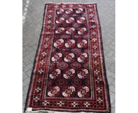 A Belouch design carpet, dark blue ground with numerous Bokhara style motifs. 9ft 0ins x 4ft 4ins.