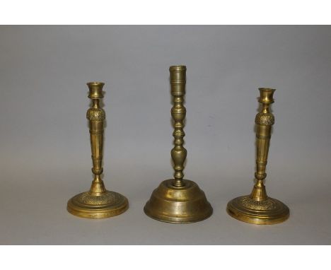 A PAIR OF 19TH CENTURY FRENCH ORMOLU CIRCULAR CANDLESTICKS, 10.5ins high, and an EARLIER BRASS STICK, 12ins high (3).