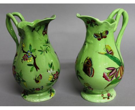 A PAIR OF POSSIBLY SPODE GREEN JUGS with enamel decoration of flowers and butterflies.Mark No. 1076.  6ins high.