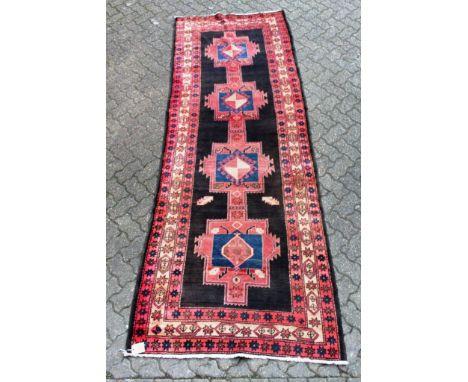 A Heriz carpet, black central field with four geometric motifs within a similar border. 10ft 8ins x 3ft 9ins.