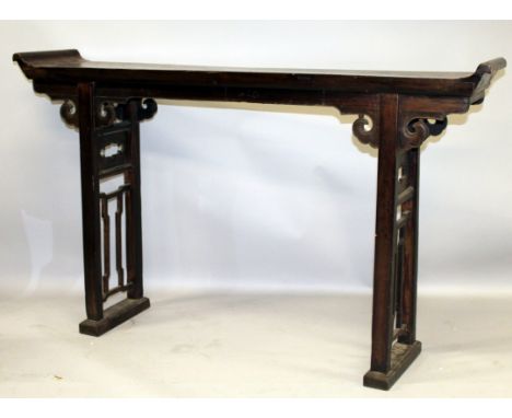 A 19TH/20TH CENTURY CHINESE CARVED HARDWOOD SCROLL END ALTER TABLE, the narrow top surface supported on two pierced rectangul