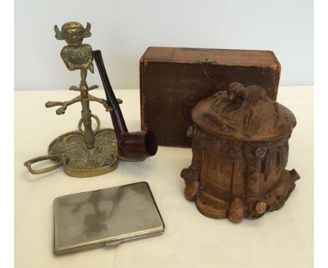 A collection of smoking items comprising a brass Lincoln Imp pipe stand with pipe, a metal cigarette case, an old wooden Cudo