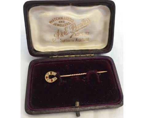 9ct gold stick pin in the shape of a horseshoe set with diamonds and rubies.