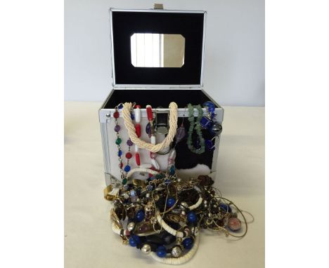 A metal jewellery case with faux fur, containing a large amount of costume jewellery.