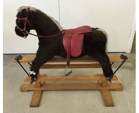 Rocking horse with leather saddle on wooden base.