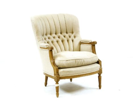 A show frame button back armchair, with cream upholstery, carved and reeded arms on fluted legs