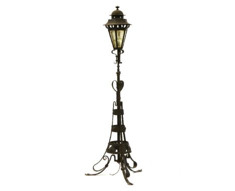 An Arts and Crafts wrought iron standard lamp in the form of a street lantern on tripod base, 170cm high