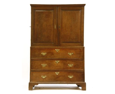 A George III oak press cupboard, the panelled doors opening to reveal slides within, over the base of three graduated long dr