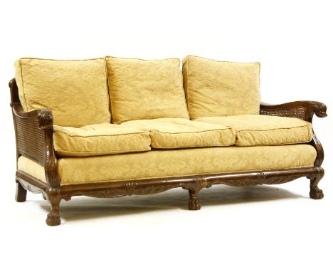 An early 20th century cased walnut bergere suite, comprising a three seater settee and a pair of armchairs, having double can