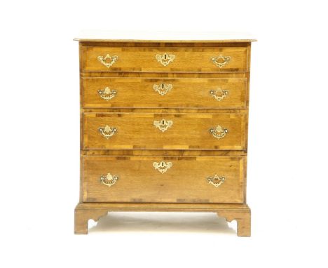 A George III oak and mahogany cross banded chest of four graduated drawers, on bracket feet