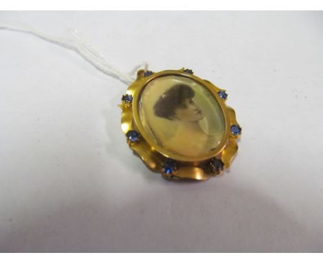 A photo locket portrait with blue stones
