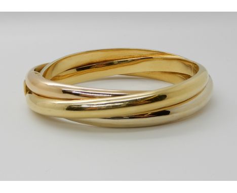AN 18CT GOLD THREE COLOUR GOLD BANGLE in the shape of Russian wedding bands, inner dimensions 5.9cm x 5cm, width approx 13.3m