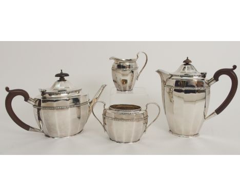 A FOUR PIECE SILVER TEA SERVICE by Adie Brothers Limited, Birmingham 1931, with oval faceted body and scrolling wooden handle