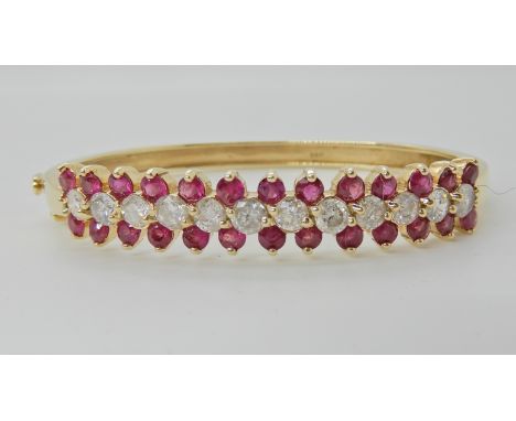 A 14K GOLD DIAMOND AND RUBY BANGLE set with estimated approx 2.40cts of brilliant cut diamonds each approx 0.20cts, inner dim
