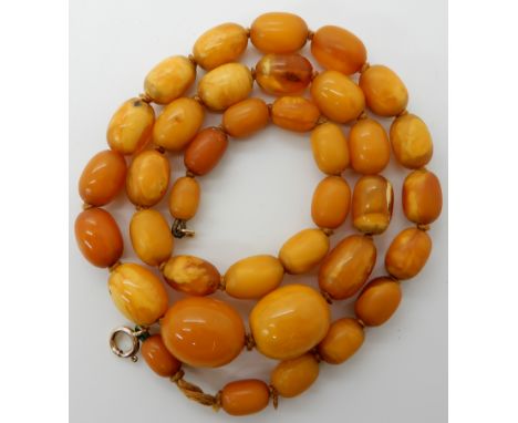 A STRING OF AMBER COLOURED BEADS largest bead approx 19.4mm x 15.7mm, smallest bead 10.5mm x 7.2mm. Length 57cm, weight 31.6g