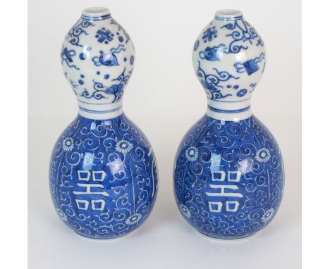 A PAIR OF CHINESE BLUE AND WHITE DOUBLE GOURD VASES painted with precious objects above Shou characters on a blue foliate scr